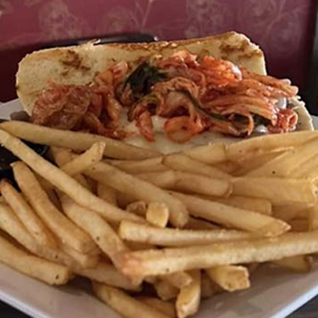 A sandwich topped with kimchi, served at our Green Bay family restaurant with French fries.