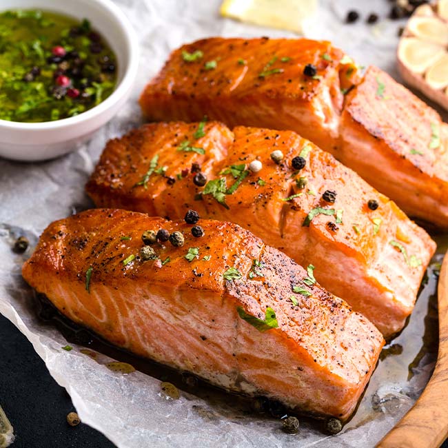 Three grilled salmon fillets with herbs at The Depot, served with green sauce.