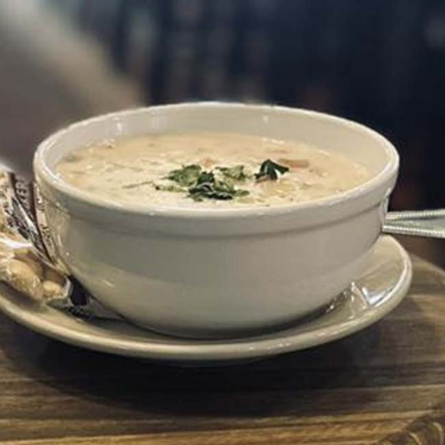 A bowl of creamy soup garnished with herbs, a perfect comfort food at any bar or café.